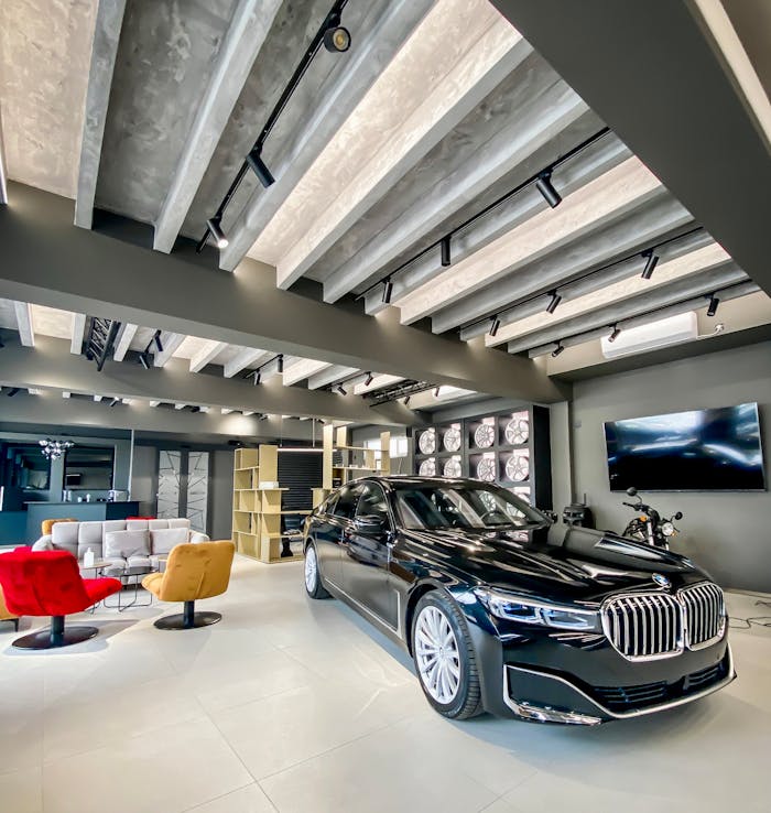Spacious showroom featuring a black luxury car, stylish armchairs, and modern decor.